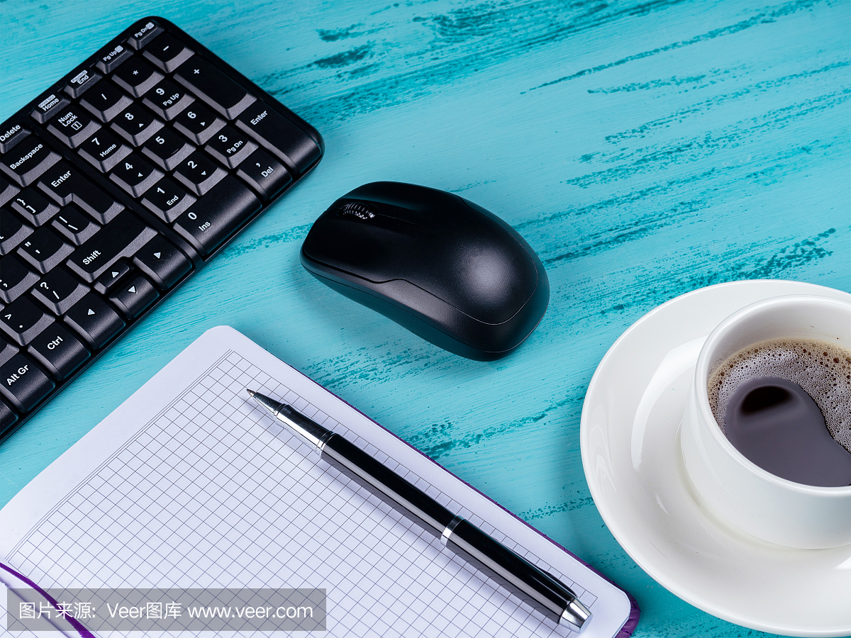 办公室桌子桌子上。工作空间与笔记本,键盘,办公用品和咖啡杯木制背景。